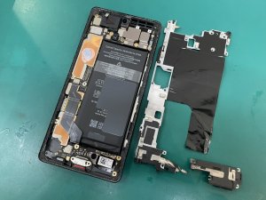 デリケートな画面パネルを慎重に開き、内部から劣化した古いバッテリーを安全に剥がしている作業の様子