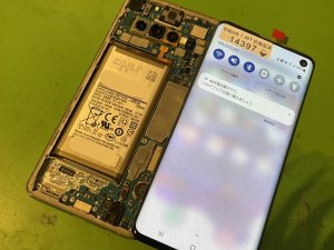 分解したGalaxyS10の基板に新しいディスプレイパネルを仮付けし、表示やタッチ機能の動作テストを行っている様子