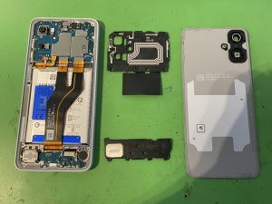 GalaxyA25の背面から慎重に分解を行い、内部の基板やバッテリーに負荷をかけないよう古い画面を取り外している様子