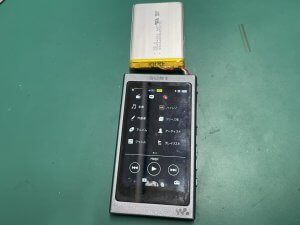 WalkmanNW-A35の基板に新しいバッテリーを取り付け、安全にハンダ付けを行って起動確認をしている様子