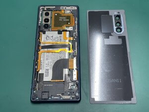 内部の複雑なケーブルに注意しながら背面からバッテリーを取り外しているXperia5