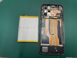 古いバッテリーを取り外し新しいバッテリーパーツを仮付けして確認しているOPPO Reno9 A